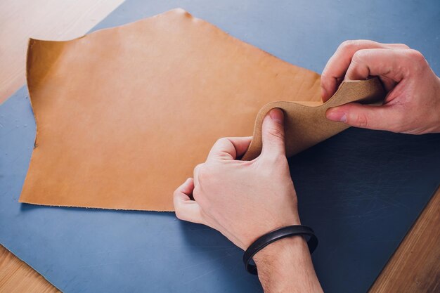 Working day in studio Man leather worker drawing sketch of purse with leather wallets and tools for sewing