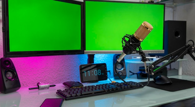 Foto workstation com microfone e monitores com tela verde para montagem