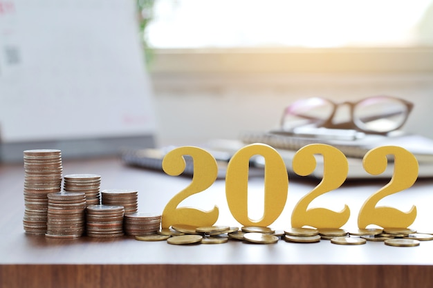 Wort 2022 auf Münzen mit Münzstapel auf dem Schreibtisch setzen. Sparkonzept für das neue Jahr.