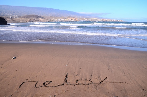 Wort auf dem Sand eines tropischen Strandes geschrieben