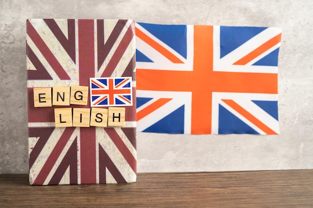 Wort Englisch auf Buch mit britischer Flagge, das Konzept für Englischkurse lernt