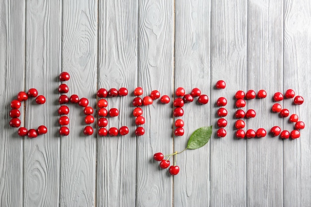 Foto wort kirschen aus süßen beeren auf holzhintergrund