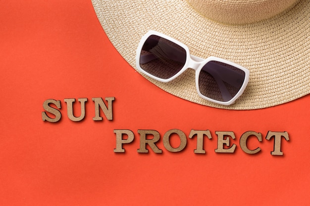 Wort Sun schützen sich vor hölzernen Buchstaben. Sonnenbrille und Hut. ba Reisekonzept