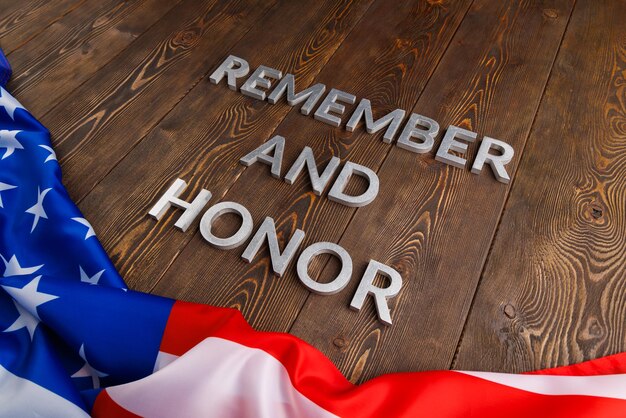 Worte erinnern und ehren mit silbernen Metallbuchstaben auf Holzhintergrund mit darunter liegender USA-Flagge