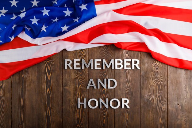 Worte erinnern und ehren mit silbernen Metallbuchstaben auf Holzhintergrund mit USA-Flagge oben