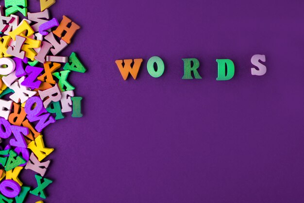 Wortwort gemacht mit blockholzbuchstaben neben einem stapel anderer buchstaben über der holzbrettoberflächenzusammensetzung