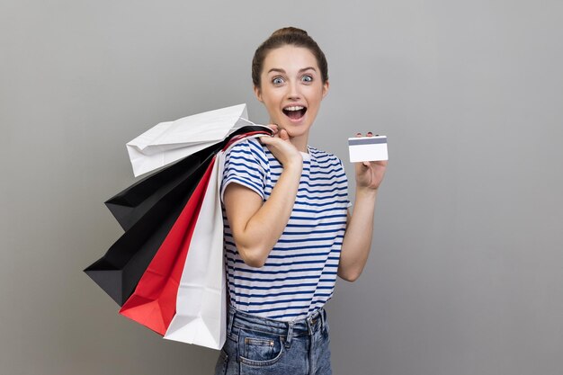 Foto wow, préstamo de compras y devolución de efectivo mujer con tarjeta de crédito y paquetes mantiene la boca abierta