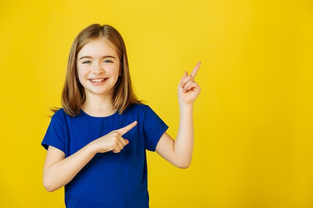 Wow, schau, wer hier das Porträt eines zufriedenen süßen kleinen Mädchens mit blauem T-Shirt annonciert, das auf einen leeren Platz zeigt ...