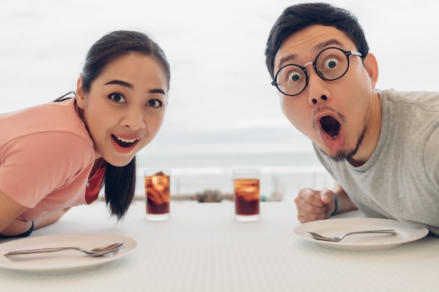 Wow und entsetztes Gesicht von Liebespaaren, die ein Date im Restaurant am Strand haben.