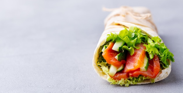 Wrap-Sandwich-Rolle mit Fisch, Lachs und Gemüse Grauer Hintergrund Nahaufnahme