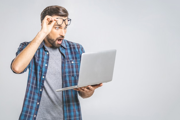 Foto wtf ?! ¡dios mio! ¡oh no! brunet emocional joven asombrado con cerdas con mueca triste mira la pantalla del dispositivo