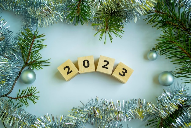 Würfel mit der Aufschrift 2023 Weihnachtsbaumzweige Lametta und Weihnachtskugeln