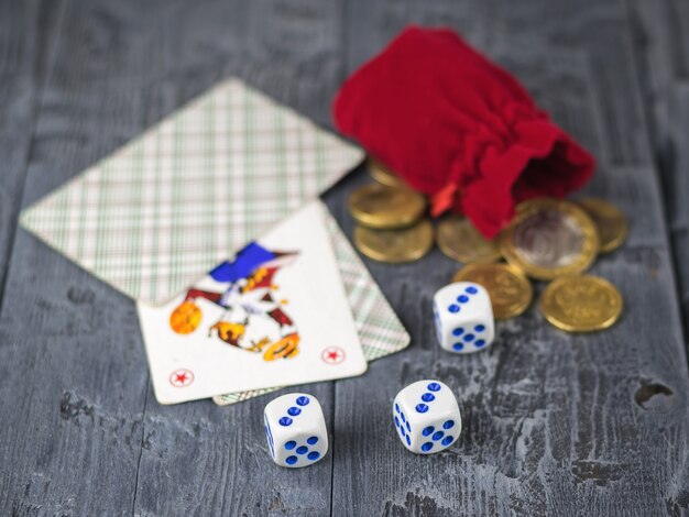 Würfel, spielkarten und eine rote geldtasche auf einem holztisch.