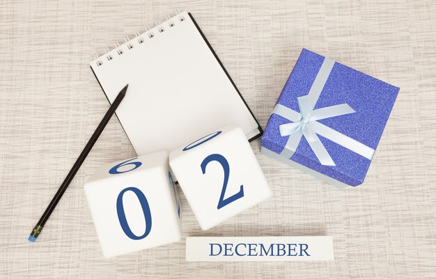 Würfelkalender für den 2. Dezember und Geschenkbox, in der Nähe eines Notizbuchs mit einem Bleistift