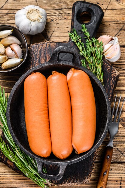 Würstchen Bratwurst aus Schweinefleisch in einer Pfanne. hölzerner Hintergrund. Draufsicht.