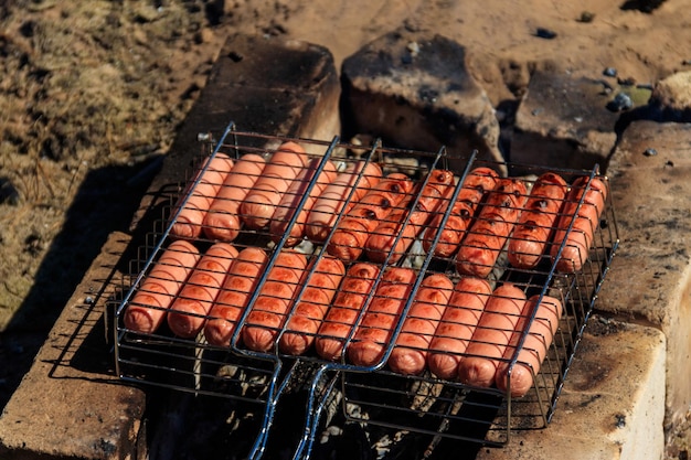 Würstchen grillen im Grillgrill kochen am Lagerfeuer