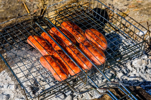 Würstchen in einem Grillgrill am Lagerfeuer kochen