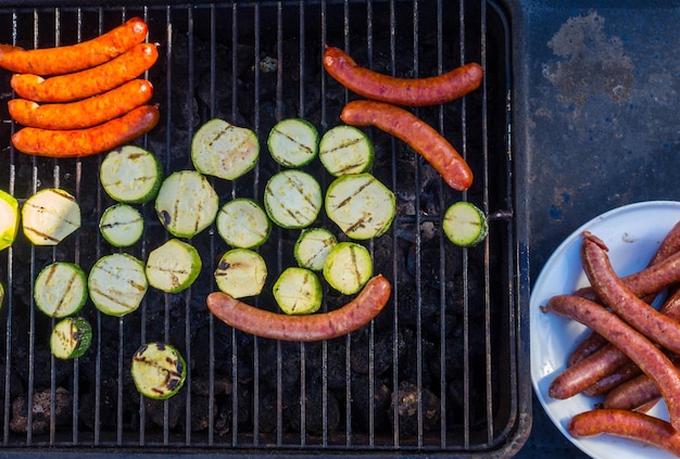 Würstchen und frisches Gemüse Zucchini Grillen auf einem Grill im Freien