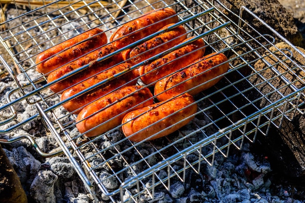 Würste, die in einem Grill am Lagerfeuer kochen