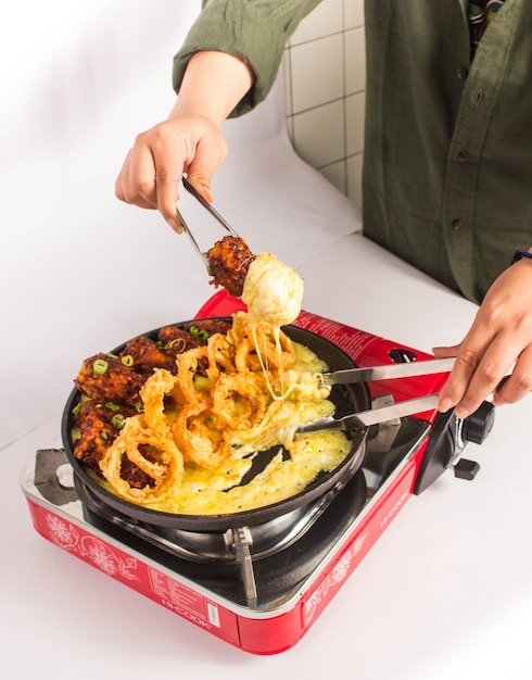 würzige Chicken Wings koreanisches Essen mit Mozzarella-Käse auf einem roten Herd