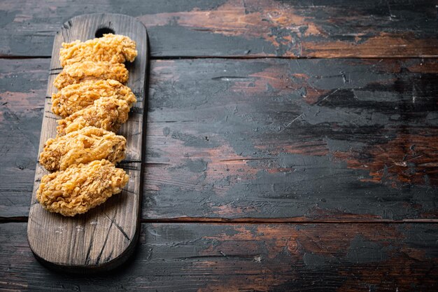 Würzige frittierte panierte Hühnerflügel schneidet auf einem alten dunklen Holztisch mit Kopierraum.
