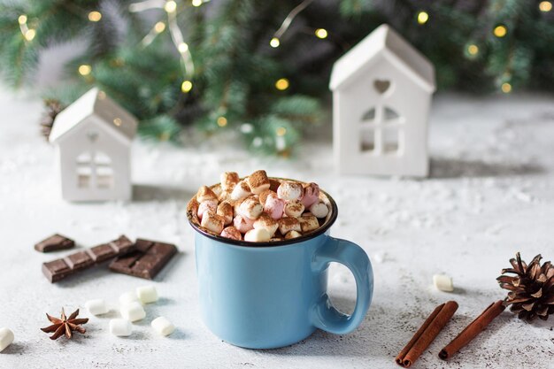 Würzige heiße Schokolade mit Zimt-Sternanis und Marshmallows in Emaille-blauem Becher auf Weiß