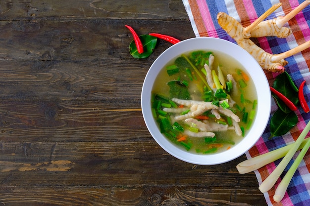 Würzige hühnerbeine suppe in der weißen schale auf holztisch