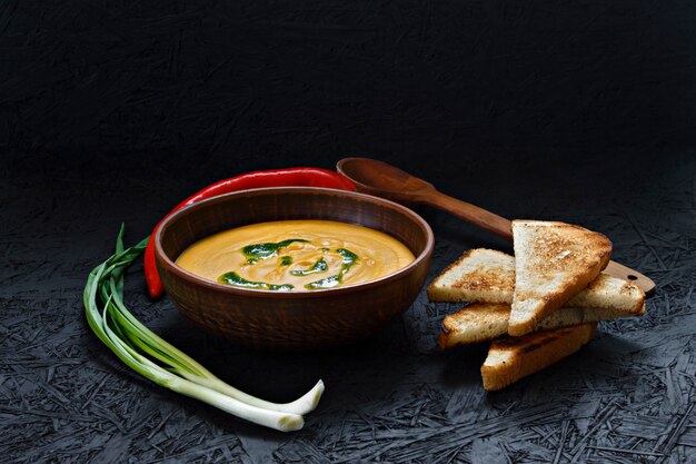 Würzige Kürbissahnesuppe mit Toast in einer Lehmplatte.