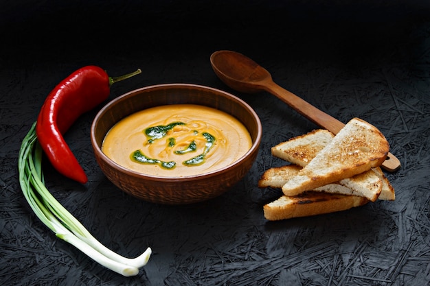 Würzige Kürbissahnesuppe mit Toast in einer Lehmplatte.