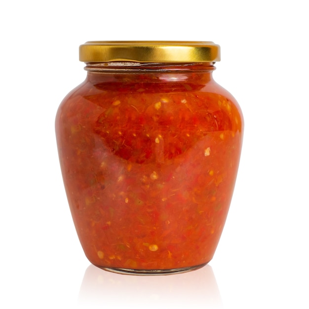 Würzige Paprika-Tomaten-Sauce Adjika in einem Glas auf weißem Hintergrund.