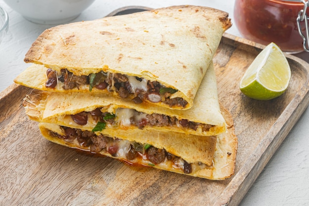 Würzige Quesadilla aus Tortilla mit Sauce und Kräutern auf weißem Grund