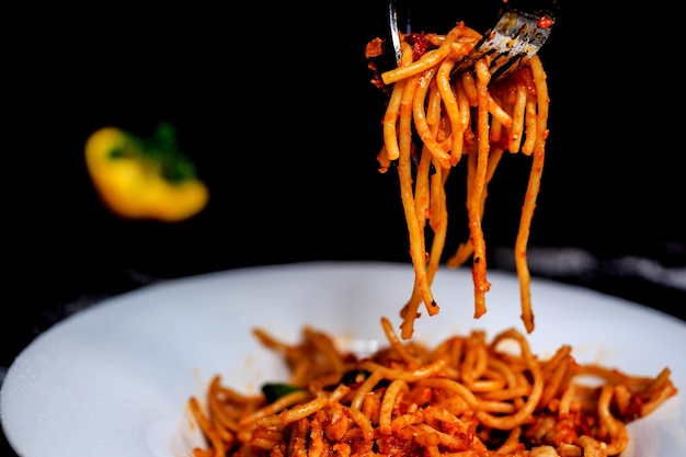 würzige Spaghetti auf Gabel und schwarzem Hintergrund