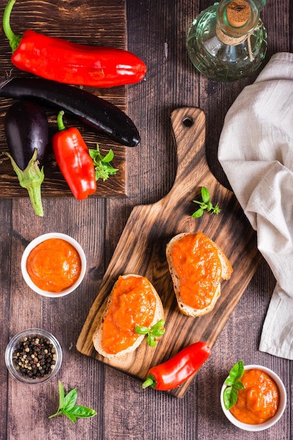 Würzige Vorspeise Ajvar auf Brotstücken und in Schalen auf dem Tisch Top und vertikale Ansicht