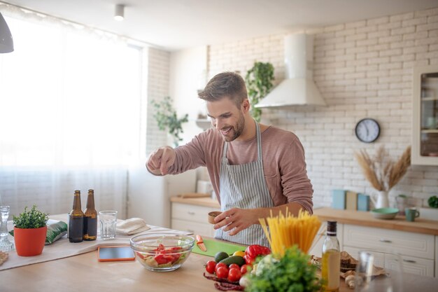 Würziger Salat. Ein Mann, der seinem Gemüsegericht Gewürze hinzufügt