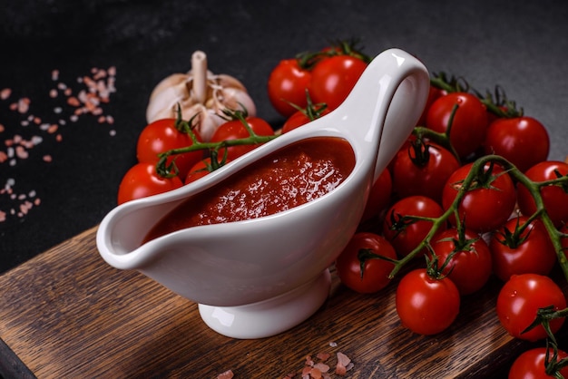 Würziges Gewürz der georgischen Küche Adjika in einer Schüssel mit roten Tomaten auf einem Betontisch in der Nähe