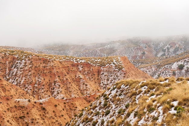 Wüste mit braunen Bergen, die teilweise mit Schnee bedeckt sind.