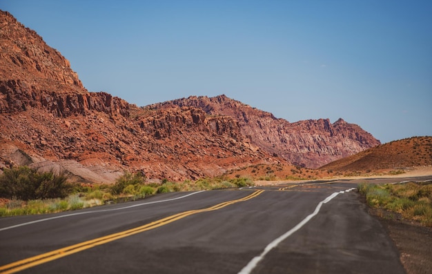 Wüstenautobahn bei Sonnenuntergang Reisekonzept USA Landschaft mit orangefarbenen Felsen Himmel mit Wolken und Asphaltstraße im Sommer Amerikanischer Roadtrip