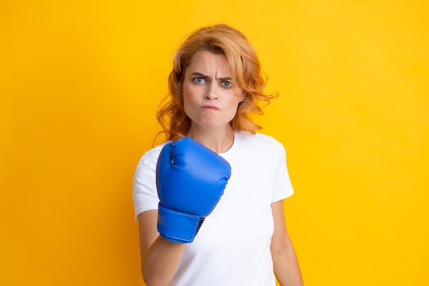 Wütende Frau in Boxhandschuhen isoliert auf gelbem Hintergrund