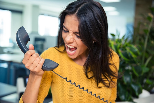 Wütende Geschäftsfrau, die im Büro am Telefon schreit