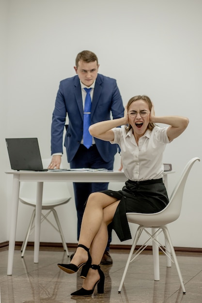 Wütender Chef schreit seinen jungen Angestellten an, sie ist gestresst und frustriert