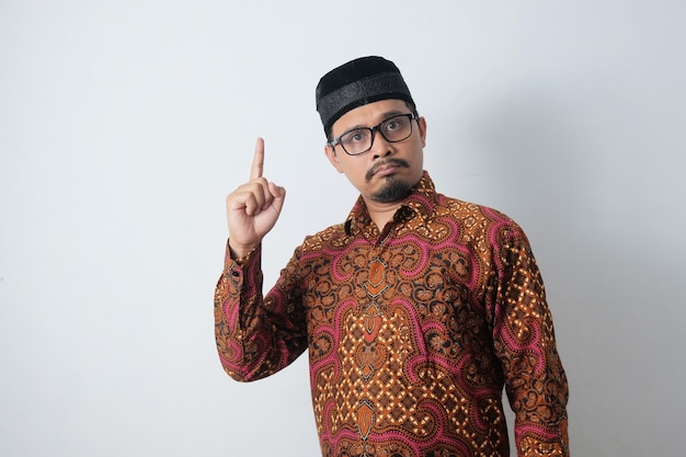 Wütender indonesischer Mann, der Batik trägt und mit dem Finger nach oben zeigt