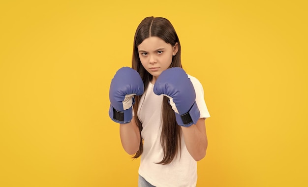 Wütendes Kind, das Boxhandschuhe auf gelbem Hintergrund einschlägt