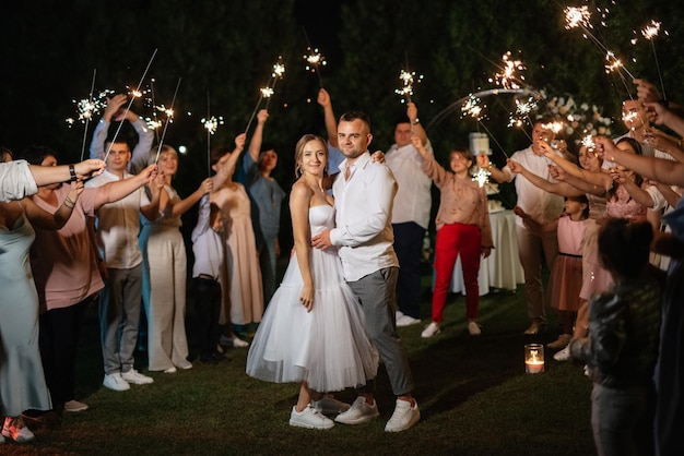 Wunderkerzen bei der Hochzeit des Brautpaares in den Händen freudiger Gäste