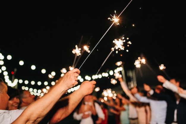 Wunderkerzen bei der Hochzeit des Brautpaares in den Händen freudiger Gäste