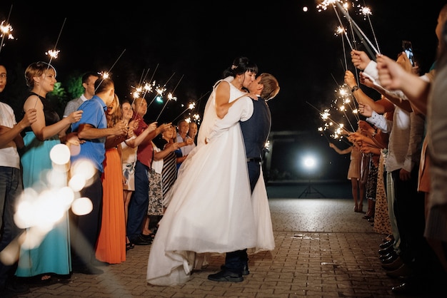 Wunderkerzen bei der Hochzeit des Brautpaares in den Händen freudiger Gäste