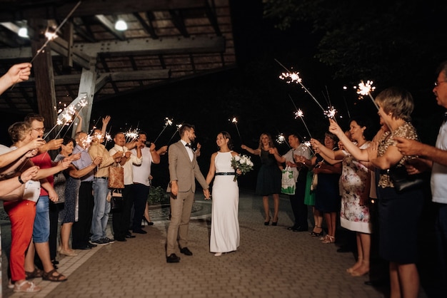 Wunderkerzen bei der Hochzeit des Brautpaares in den Händen freudiger Gäste