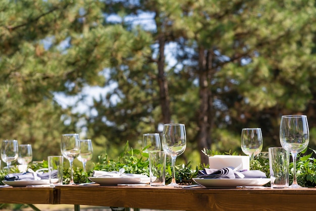 Wunderschön dekorierter Holztisch in einem Sommercafé unter freiem Himmel. Tischdekoration mit grünem Zweig und frischen Blumen.