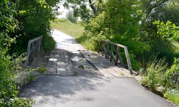 Wunderschön stehende alte Holzbrücke über den Fluss in farbigem Hintergrund Nahaufnahme, bestehend aus alter Holzbrücke über dem Fluss im Laub alte Holzbrücke am Fluss für einen natürlichen Wildpark