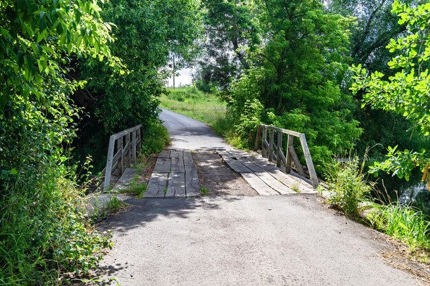 Wunderschön stehende alte Holzbrücke über den Fluss mit farbigem Hintergrund, Nahaufnahme, bestehend aus einer alten Holzbrücke über dem Fluss im Laubwerk, einer alten Holzbrücke am Fluss für einen natürlichen Wildpark