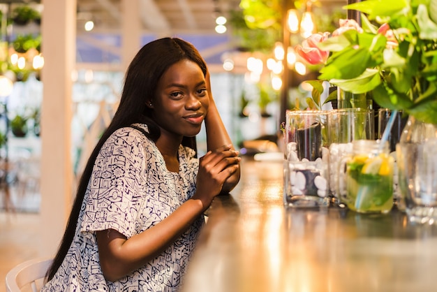 Wunderschöne afrikanische Frau, die Limonade trinkt, die im Café sitzt.